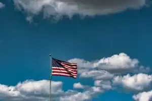 Closeup shot of the American flag waving in the air under a cloudy sky; roseville 4th of july